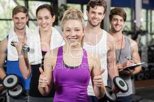 Fitness group lifting dumbbells and showing thumbs up
