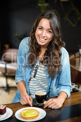 Smiling brunette drinking coffee and eating pastry