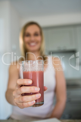 Pretty blonde woman holding her homemade smoothie