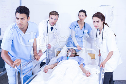 Concerned doctors standing near patient on bed
