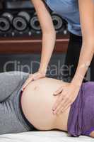 Trainer touching belly of lying pregnant woman