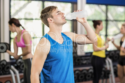 Muscular man posing with athletic women behind