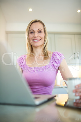 Pretty blonde woman having coffee and using laptop