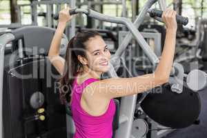 Fit woman using weight machine