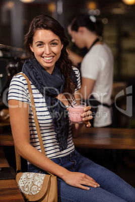 Smiling brunette drinking a beverage