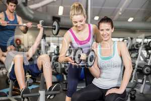 Trainer woman helping woman lifting dumbbell