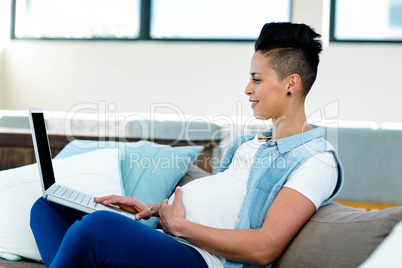 Pregnant woman relaxing on sofa with her laptop Pregnant woman relaxing on sofa with her laptop