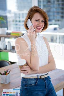 smiling hipster business woman sitting on her desk on the phone