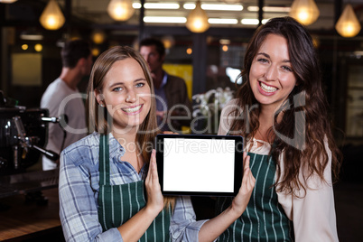 Pretty baristas showing tablet screen at the camera