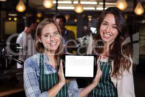 Pretty baristas showing tablet screen at the camera