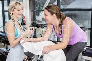 Trainer using stopwatch while pregnant woman is using exercise b