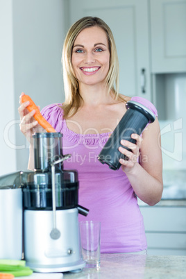 Blonde woman preparing a smoothie in the kitchen