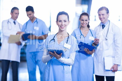 Female doctor using tablet and smiling at camera