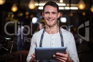 Smiling barista holding tablet and looking at the camera