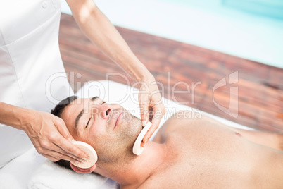 Man receiving a facial massage from masseur