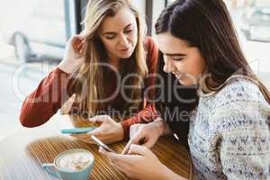 Friends using smartphone and having coffee