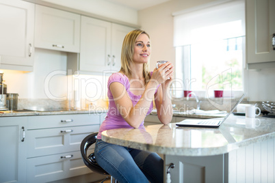 Pretty blonde woman having coffee and using laptop