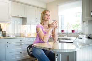 Pretty blonde woman having coffee and using laptop