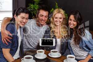 Smiling friends enjoying coffee and taking selfie