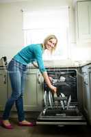 Pretty blonde woman emptying the dishwasher