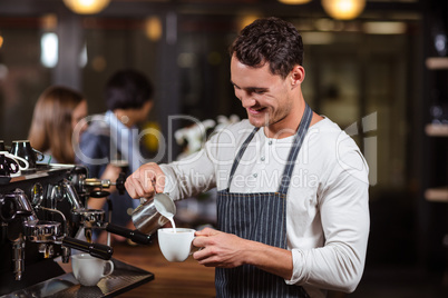 Smiling barista preparing cappuccino