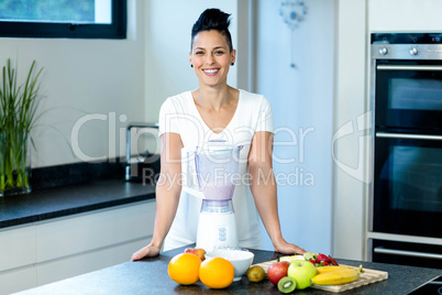 Pregnant woman standing near worktop with blender and fruits