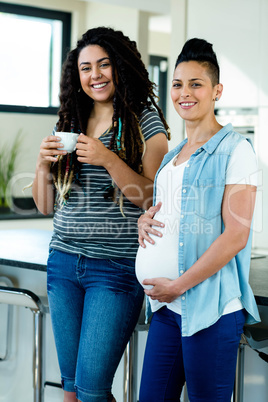 Portrait of pregnant lesbian couple standing together