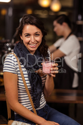 Smiling brunette drinking a beverage