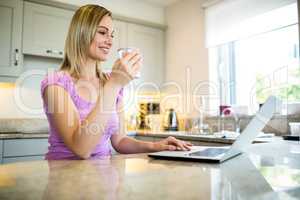 Pretty blonde woman having coffee and using laptop