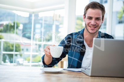 Handsome man working on laptop with cup of coffee