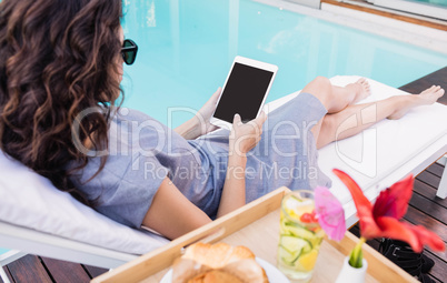 Young woman using digital tablet near poolside