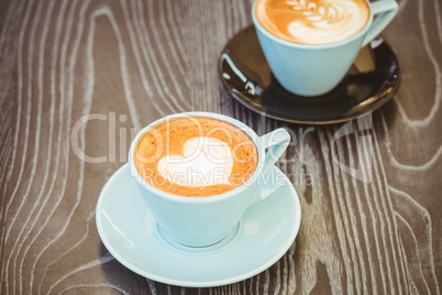 Cup of cappuccino with coffee art on wooden table