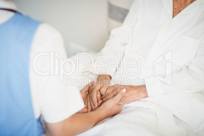 Senior woman and nurse holding hands