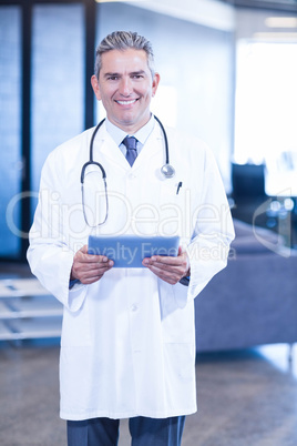 Doctor holding digital tablet and smiling at camera