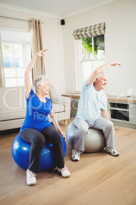 Senior couple doing stretching exercise on exercise ball Senior couple doing stretching exercise on exercise ball