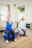 Senior couple doing stretching exercise on exercise ball