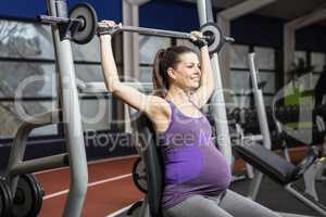Smiling pregnant woman lifting barbell