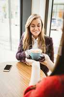 Cute blonde girl having a coffee served by her friend