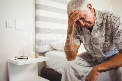 Frustrated senior man sitting on bed