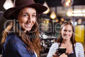 Smiling woman holding coffee looking back at the camera