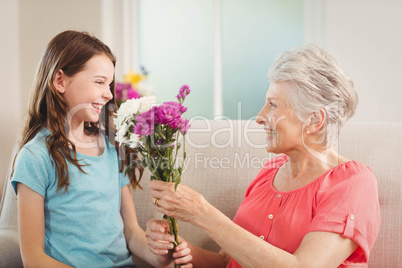 Grandmother giving a bunch of flowers to her granddaughter