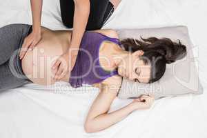 Trainer touching belly of lying pregnant woman