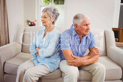 Sad senior couple sitting on sofa