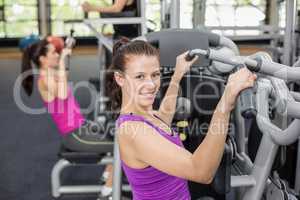 Fit woman using weight machine