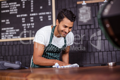 Smiling barista cleaning counter