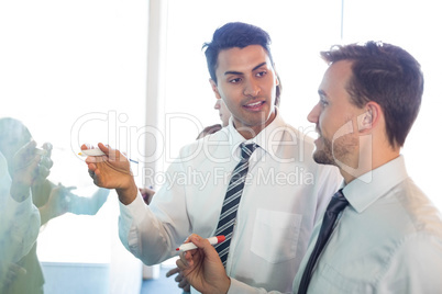 Businesspeople writing on white board