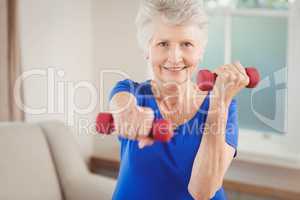 Portrait of senior woman exercising with dumbbells