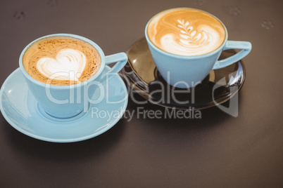 Cup of cappuccino with coffee art on wooden table