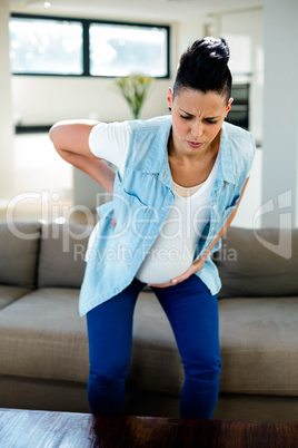 Pregnant woman bending forward with hand on hip