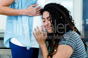 Woman listening to pregnant partners stomach